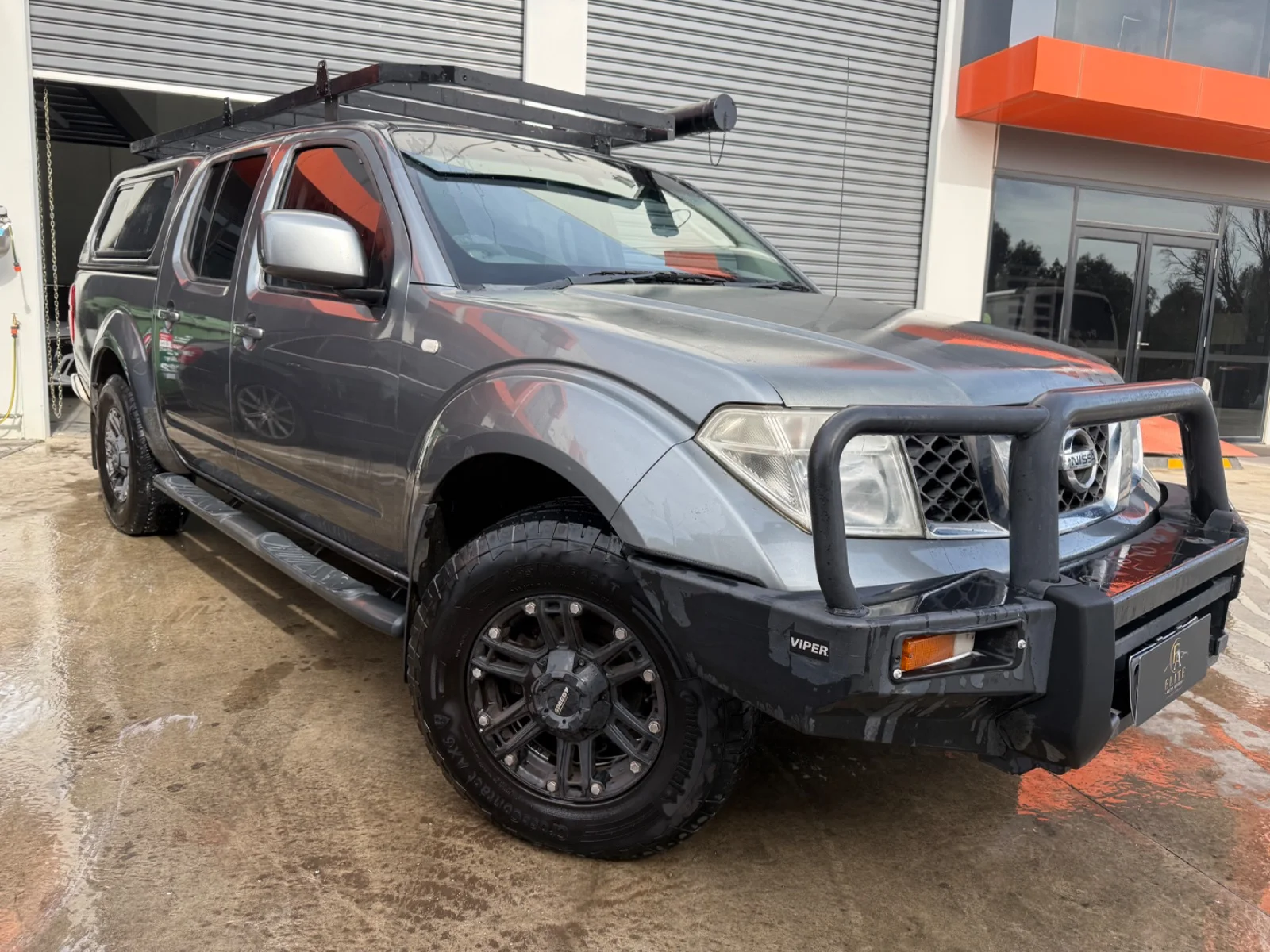 Front three-quarter view of a silver 2010 Nissan Navara ST 4x4 dual cab with bull bar.