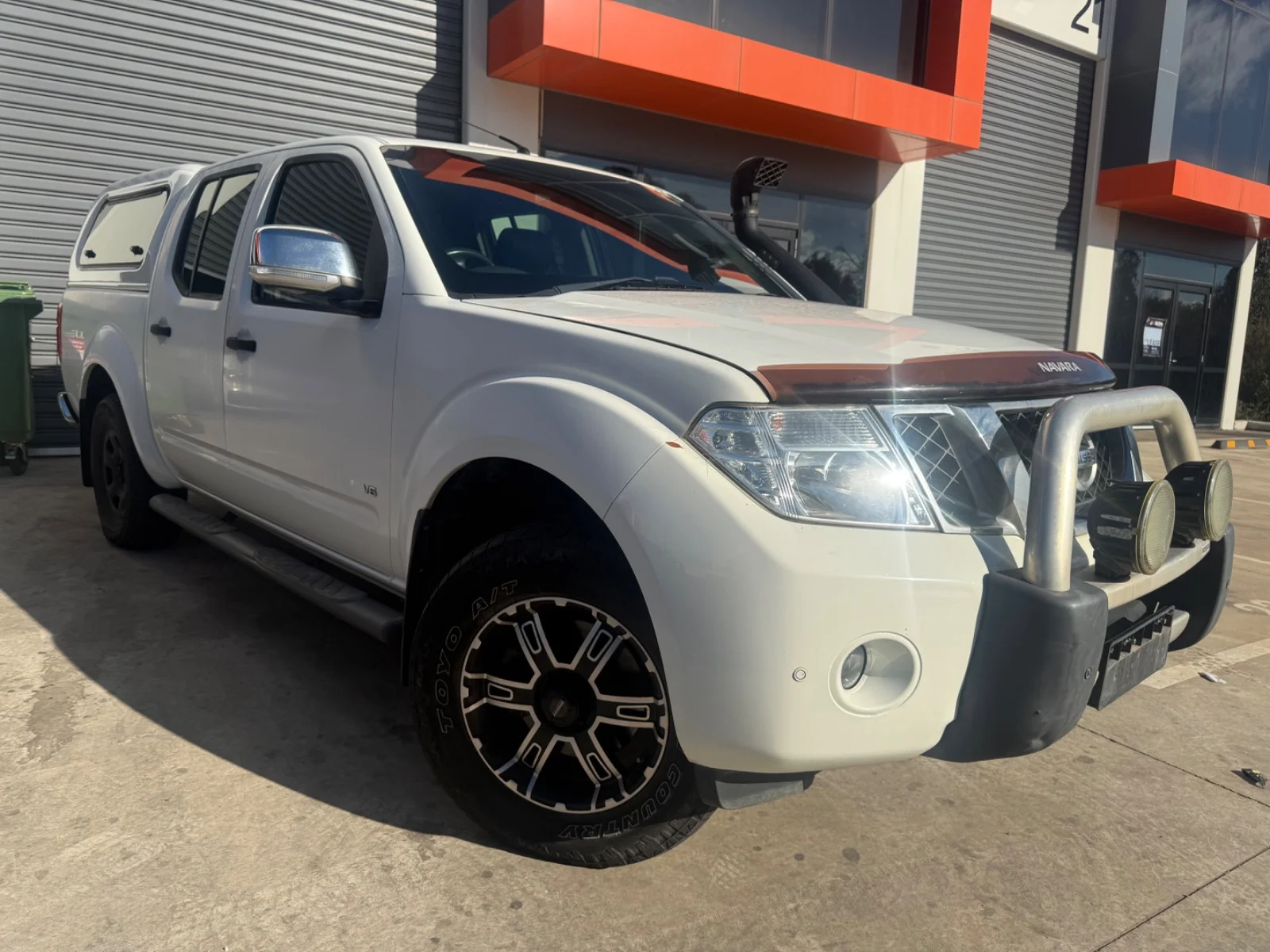 Front three-quarter view of a white 2013 Nissan Navara ST-X 4x4 dual cab with canopy.